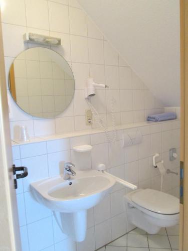 a bathroom with a sink and a toilet and a mirror at Landhotel Karrenberg in Kirchberg