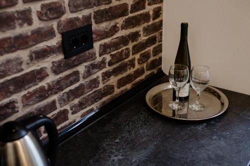 a table with two glasses and a bottle of wine at Apartmani Galea in Sombor