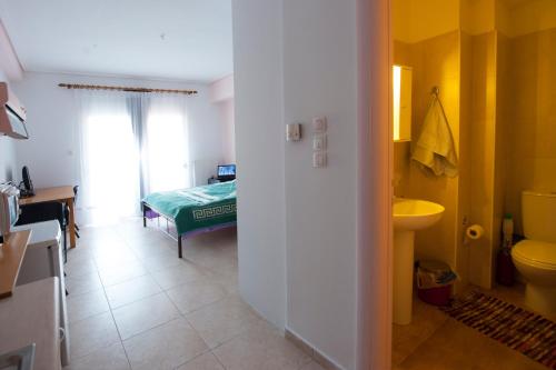 a bathroom with a sink and a toilet and a bed at Elias Appartment in Volos