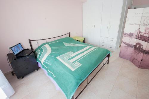 a bedroom with a bed with a green blanket on it at Elias Appartment in Volos
