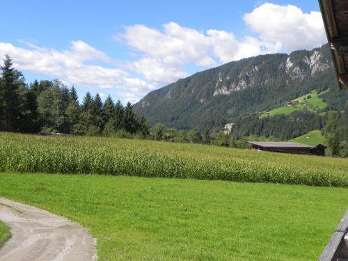 a field of green grass with a barn and mountains at Schwaighof in Oberau