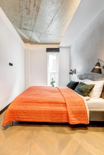 a bedroom with a large bed with an orange blanket at HaPPy Inn Presidential, Self check-in, Parking in the underground garage in Vilnius