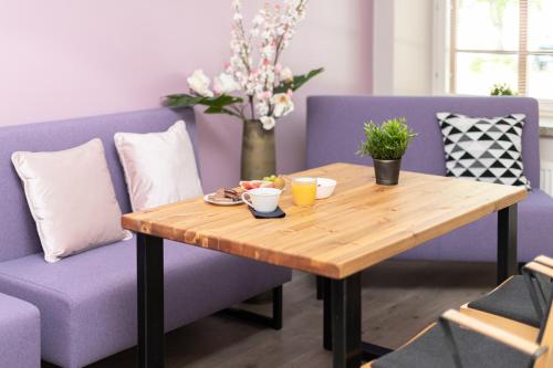 a table and chairs with a purple couch and a table at Hotelli Rakuuna in Lappeenranta