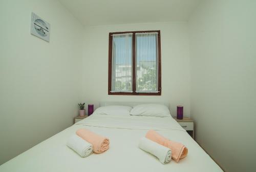 a white bed with two pink pillows on it at Serenity by the Sea #1 - private terrace in Vrsi