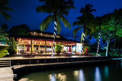 a building with palm trees in front of a body of water at Nanajuana Río Dulce in Rio Dulce