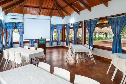 a room with white tables and chairs and a screen at Nanajuana Río Dulce in Rio Dulce