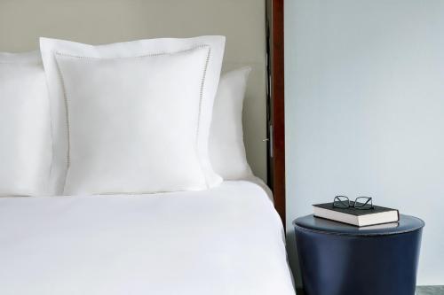 a bed with white pillows and a book on a stool at Royalton New York in New York