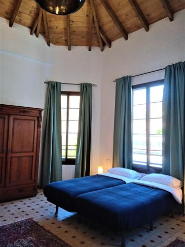 a bedroom with a bed with blue sheets and windows at El Cielo Azul in Alora