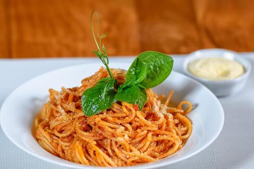 a white plate of pasta with basil on top at Aryana Boutique Hotel in Anuradhapura