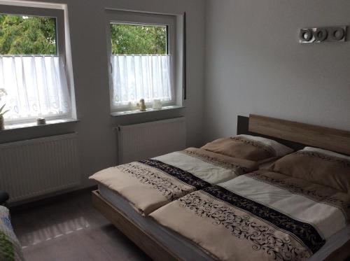 una camera da letto con un grande letto con due finestre di Ferienwohnung Lahntal Limburg a Limburg an der Lahn