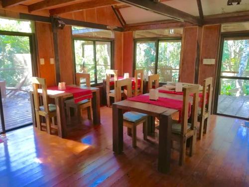 uma sala de jantar com mesas, cadeiras e janelas em Surucua Reserva & Ecolodge em Comandante Andresito
