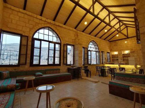 uma grande sala com mesas, cadeiras e janelas em Turquoise em Nablus