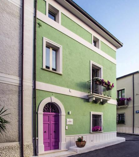 a green building with a purple door and a balcony at B&B La Mia Valigia in San Lucido