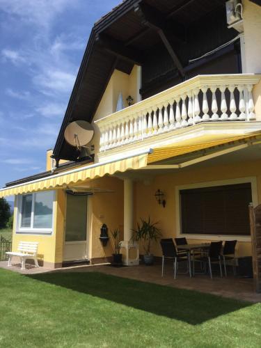 a yellow house with a balcony and a table at Appartements Panorama Schlössl in Velden am Wörthersee