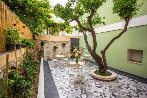 a courtyard with a tree and chairs and flowers at B&B La Mia Valigia in San Lucido