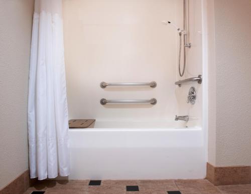 Larkspur Landing Pleasanton-An All-Suite Hotel في بليزانتون: دش في الحمام مع ستارة الدوش