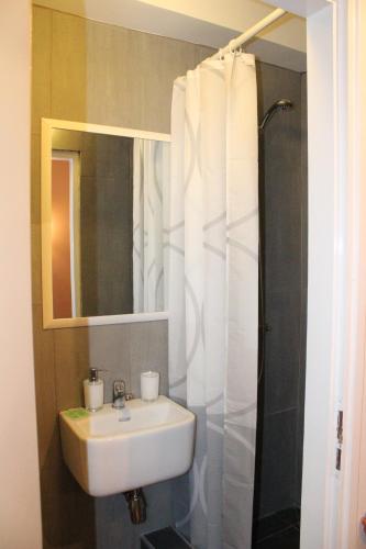 a bathroom with a sink and a shower with a mirror at Rooms Zagreb 17 in Zagreb