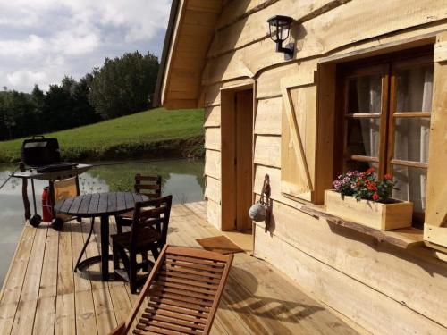 a wooden deck with a table and chairs on a house at La cabane du pêcheur in Montcuq