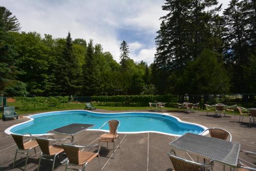 a swimming pool with chairs and a table and chairs at Auberge Alpine Inn in Sainte-Adèle