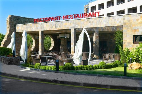 a restaurant with chairs and umbrellas in front of a building at Park Hotel Green Europe in Haskovo