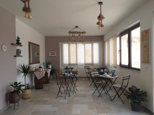 una sala da pranzo con sedie, tavoli e finestre di B&B Marsà a Marzamemi