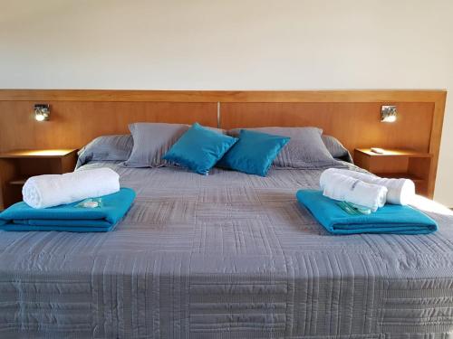 a large bed with two blue pillows on it at Posada de la comarca in Sierra de la Ventana