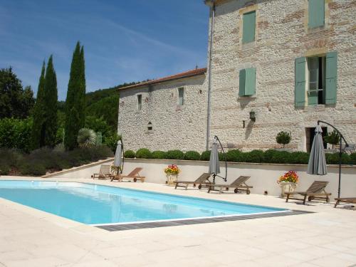 - une piscine avec des chaises et des parasols à côté d'un bâtiment dans l'établissement La Maison de Maitre, à Sainte-Livrade-sur-Lot