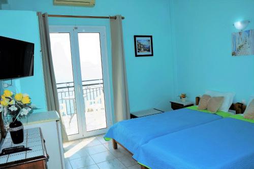 a blue bedroom with a bed and a balcony at Hotel Perama in Perama
