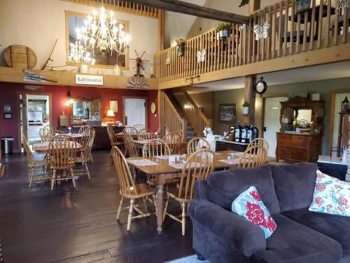 a dining room with a couch and tables and chairs at The Barn Inn Bed and Breakfast in Millersburg