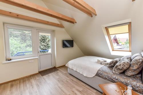 a bedroom with a bed and two windows at "Pamario mansarda" - Preiloje in Neringa