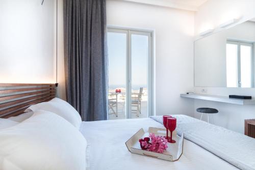 a hotel room with a bed with a tray of flowers on it at Wabi Luxury Suites & Maisonettes Ios in Ios Chora