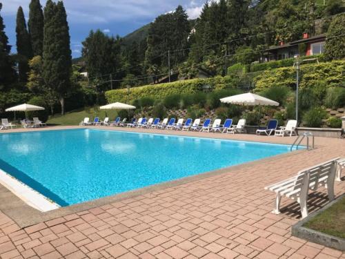 a large blue swimming pool with chairs and umbrellas at Residenza del Pascià - Appartamento Camphora in Oggebbio