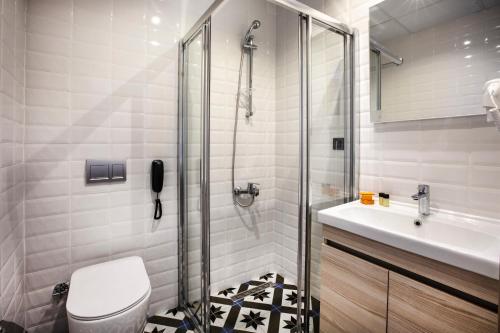 a bathroom with a shower and a toilet and a sink at Eliada Hotel in Kuşadası