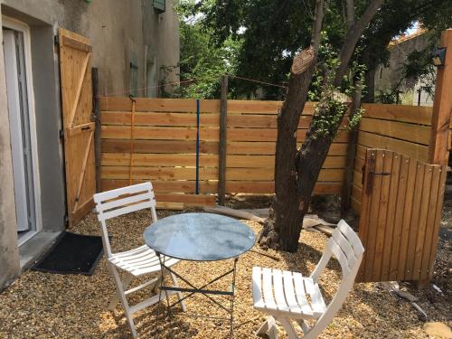 una mesa y dos sillas y un árbol en un patio en CHARMANT STUDIO, en Capestang