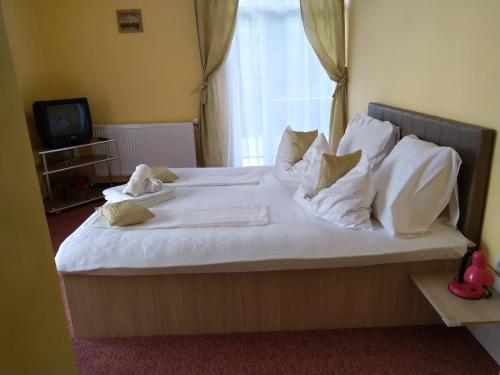 1 dormitorio con 1 cama con sábanas y almohadas blancas en Casa Crina, en Baile 1 Mai