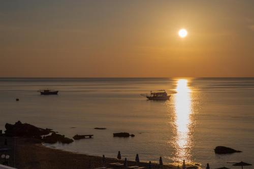 a sunset over the water with boats in the ocean at Apágkio Filoxenia in Archangelos