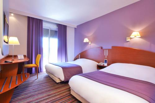 Un pat sau paturi într-o cameră la Kyriad Bourg En Bresse