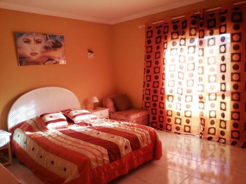 a bedroom with a bed and a chair and a window at Casa Nuno in Lagoa