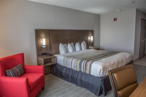 a hotel room with a bed and a red chair at Country Inn & Suites by Radisson, Harlingen, TX in Harlingen