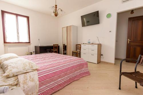 1 dormitorio con 1 cama y TV en la pared en La Colomba B&B, en Castellaro