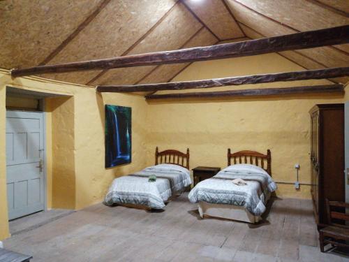 two beds in a room with a wooden ceiling at Casa rural la cruz in Agüimes