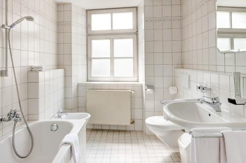 a white bathroom with a tub and a toilet and a sink at Brauereigasthof/Hotel Bürgerbräu in Bad Reichenhall