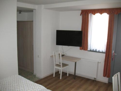 a bedroom with a desk and a tv on the wall at Pension Hinz & Kunz in Weimar