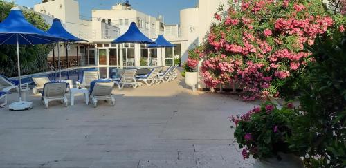 a patio with chairs and umbrellas next to a pool at Bodrum Blu Hotel in Bodrum City