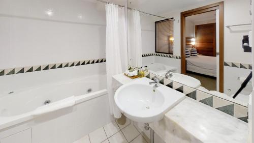 a bathroom with two sinks and a bath tub and a mirror at Silkari The Pavilions in Port Douglas