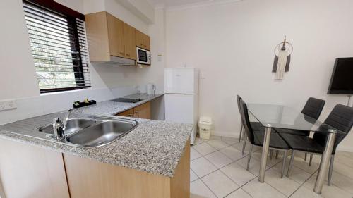 a kitchen with a sink and a table with chairs at Silkari The Pavilions in Port Douglas