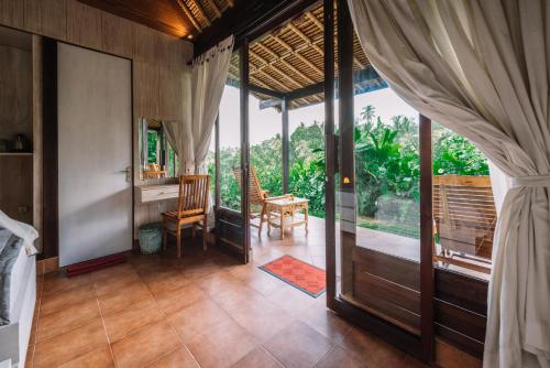 a room with a bed and a table and a window at Bersila La Maison Du Bonheur in Payangan