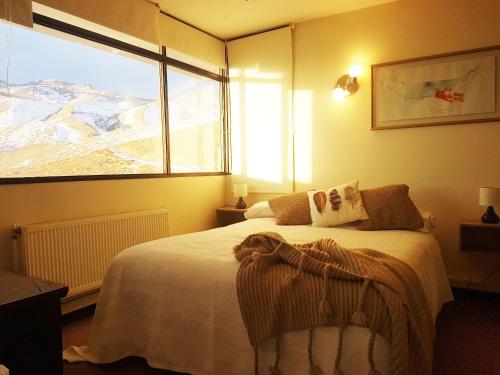 a bedroom with a bed and a large window at El Colorado Ski Departamentos in El Colorado