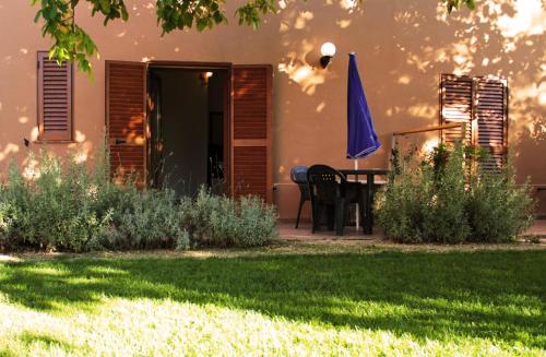 un patio con una mesa y una sombrilla azul en Agriturismo San Mauro en Capalbio