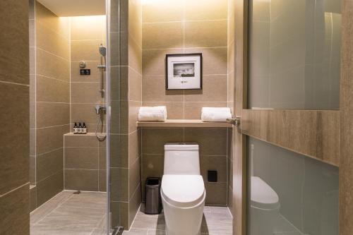 La petite salle de bains est pourvue d'une douche et de toilettes. dans l'établissement Atour Hotel Qingdao Airport Chengyang Wanxianghui, à Qingdao